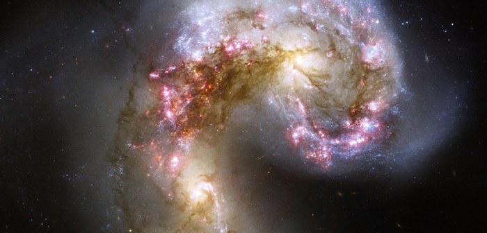 Les Galaxies des Antennes, deux spirales en pleine collision dont les bras déformés brillent de milliers de jeunes amas d'étoiles roses