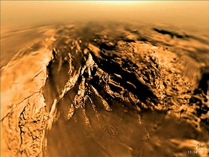 Vue en fisheye du relief de Titan capturée par la sonde Huygens durant sa descente en parachute, montrant des chenaux de drainage sculptés dans le terrain